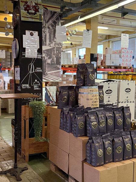 Blick in eine Kaffee-Lagerhalle, im Vordergrund stehen Kaffees der Marke "Espresso International" aufgetürmt